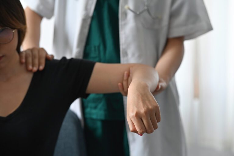 Médica segurando braço e examinando ombro de paciente.